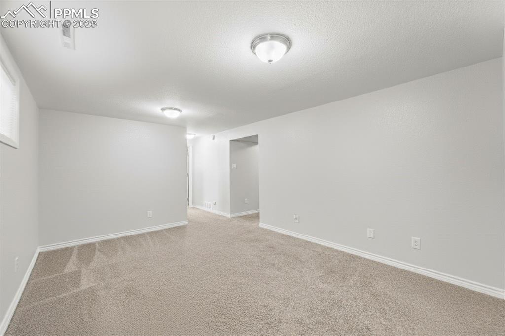 Image 26 of 48: Empty room featuring carpet and a textured ceiling