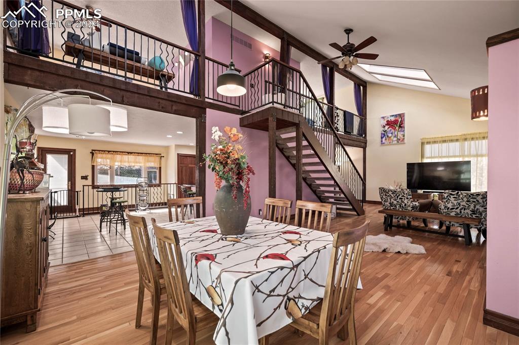 Image 13 of 48: Dining space with ceiling fan, lofted ceiling with skylight, and light wood