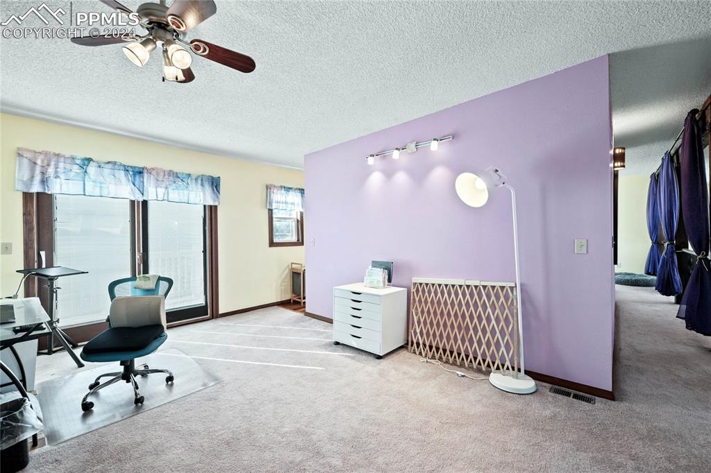 Image 27 of 48: Primary Suite Carpeted home office with a textured ceiling and ceiling fan