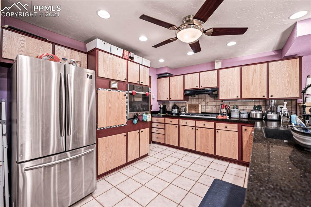 Image 28 of 48: Kitchen with tasteful backsplash, stainless steel appliances, ceiling fan, 