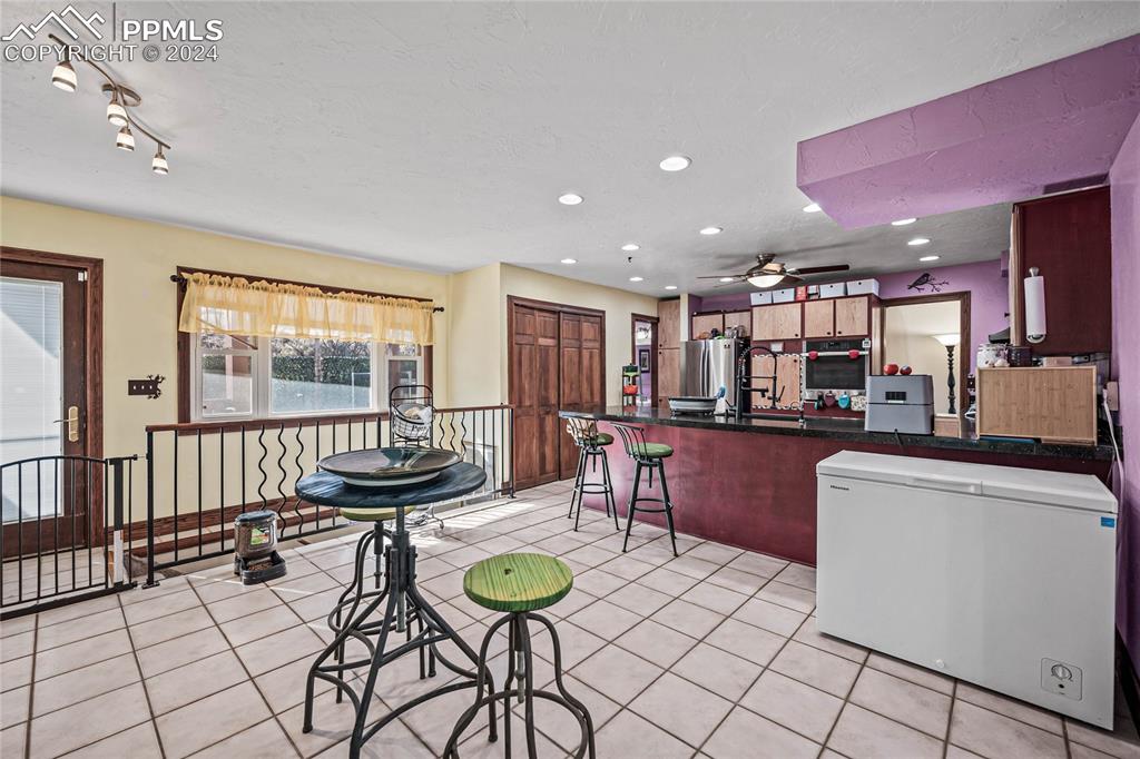 Image 33 of 48: Kitchen with kitchen peninsula, ceiling fan, light tile patterned flooring,