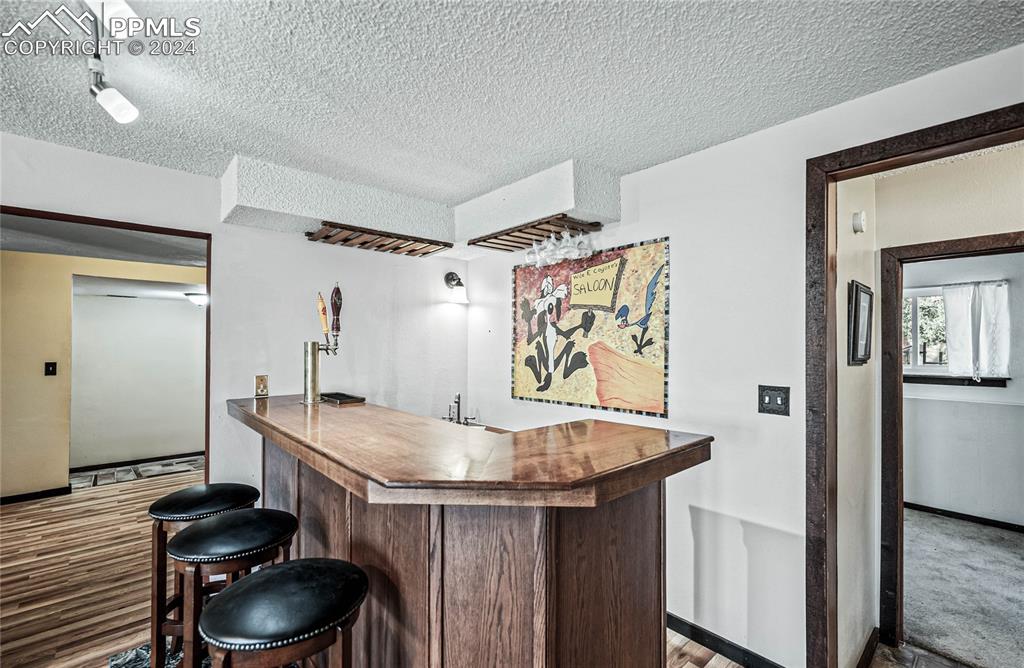 Image 41 of 48: Bar featuring carpet flooring, elevator, and a textured ceiling