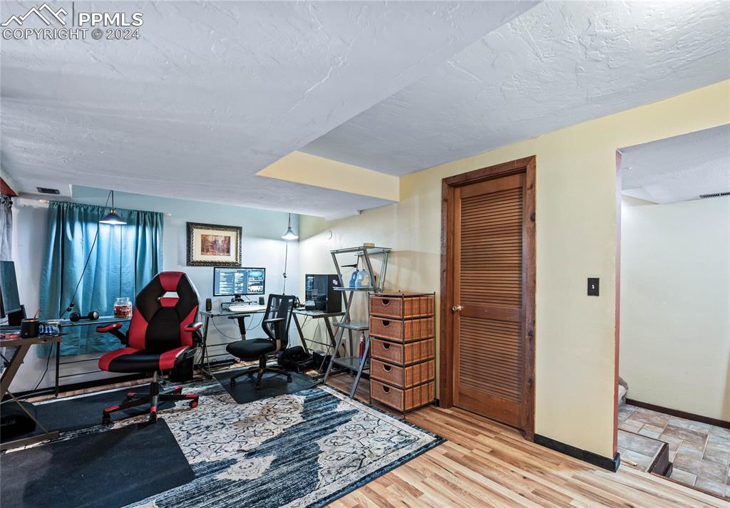 Image 44 of 48: Basement Office/Exercise area featuring a textured ceiling and light wood-t