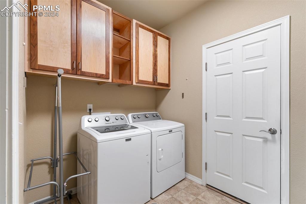 Image 23 of 39: Main level laundry connects garage and kitchen; custom cabinets.