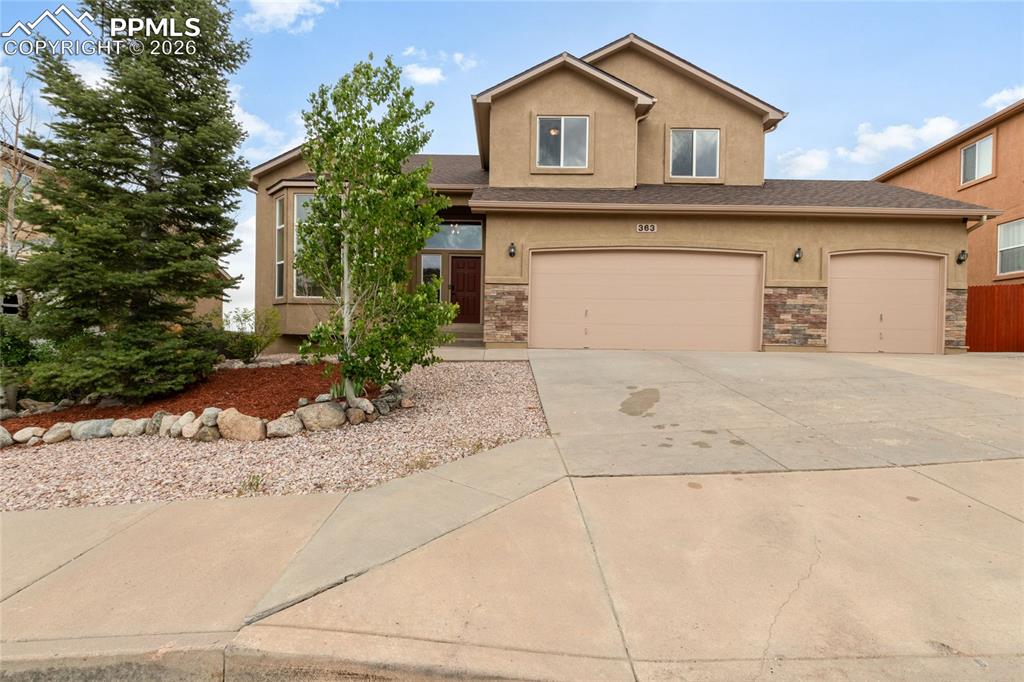 Image 1 of 35: Stucco exterior featuring stone veneer accents, a three-car garage, and a c