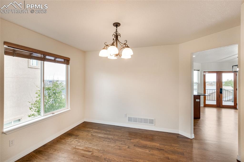 Image 11 of 35: Dining area featuring wood-finish flooring, a large window with wood blinds