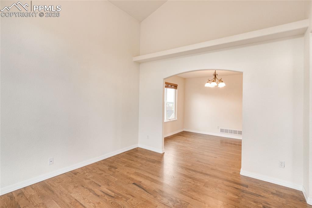 Image 12 of 35: Living room featuring wood-finish flooring and arch doorway to dining room.