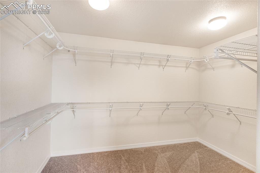 Image 22 of 35: Spacious walk-in closet in primary bedroom, featuring white wire shelving,