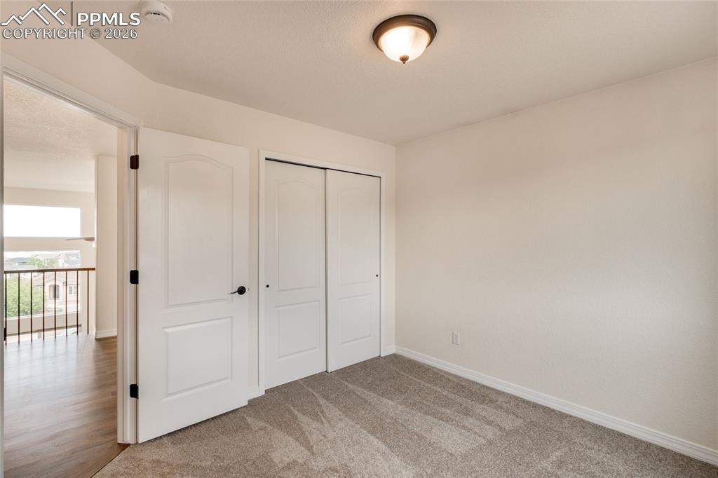 Image 24 of 35: Second upstairs bedroom with white walls and a closet with sliding doors.