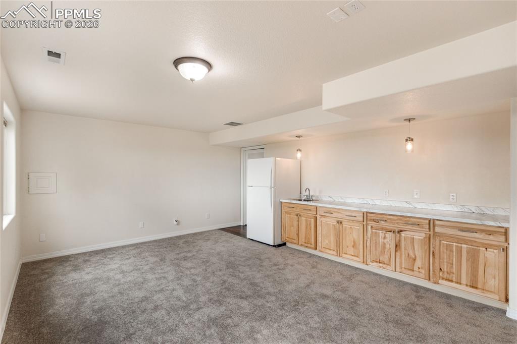 Image 28 of 35: Additional view of bonus room featuring wood cabinetry, counter top with si