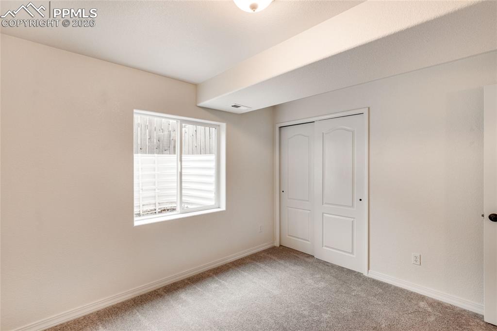Image 29 of 35: First basement bedroom with window and closet with sliding doors.