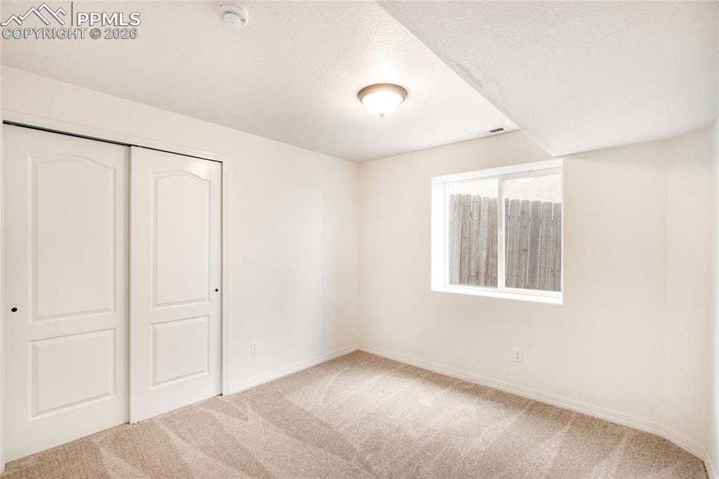 Image 30 of 35: Second basement bedroom featuring a single window and closet with sliding d