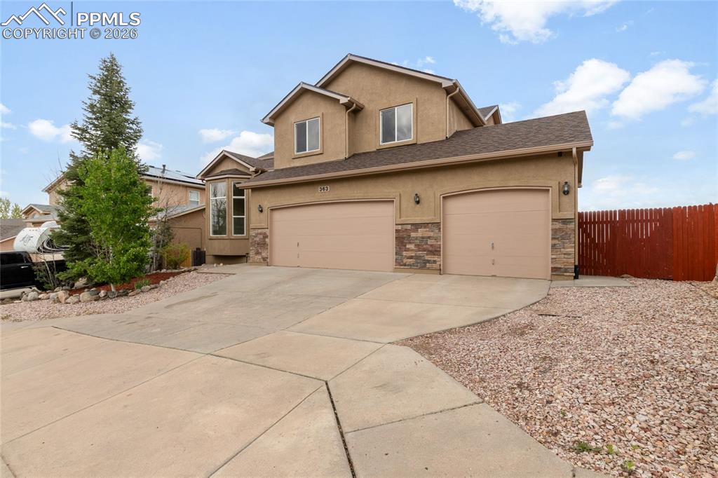Image 31 of 35: Stucco exterior featuring stone veneer accents, a three-car garage, and a c
