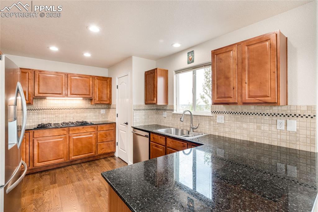 Image 7 of 35: Kitchen featuring rich wood cabinetry, dark speckled countertops, GenAir co