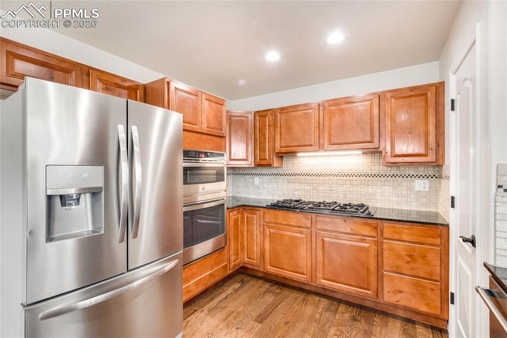 Image 8 of 35: Stainless Steel appliances, rich wood cabinetry, GenAir cooktop and corner