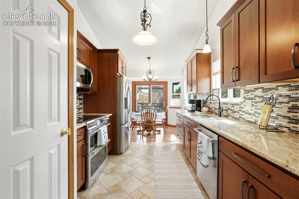 Image 6 of 32: Kitchen featuring warm wood cabinetry with dark hardware, stainless steel a