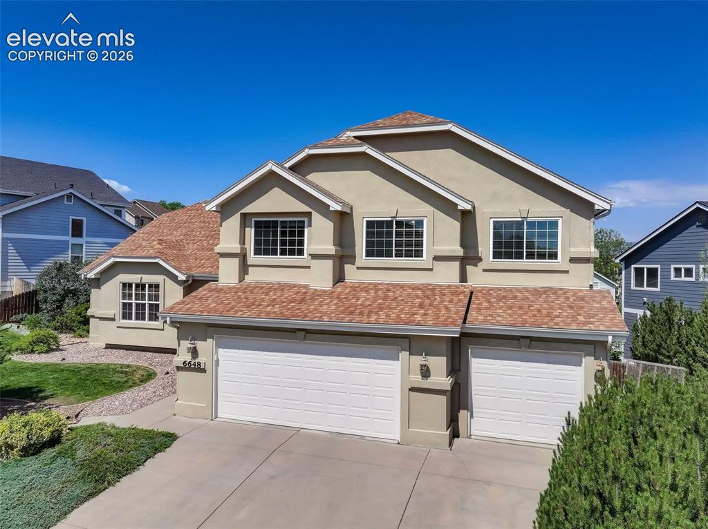 Caption: Two-story stucco exterior featuring a multi-gabled roof, multiple windows, and an integrated two-car