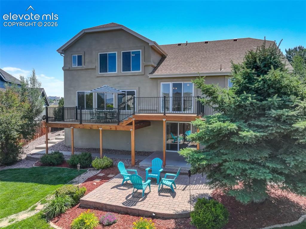 Image 1 of 49: Rear exterior featuring a spacious wooden deck with black railings, a lower
