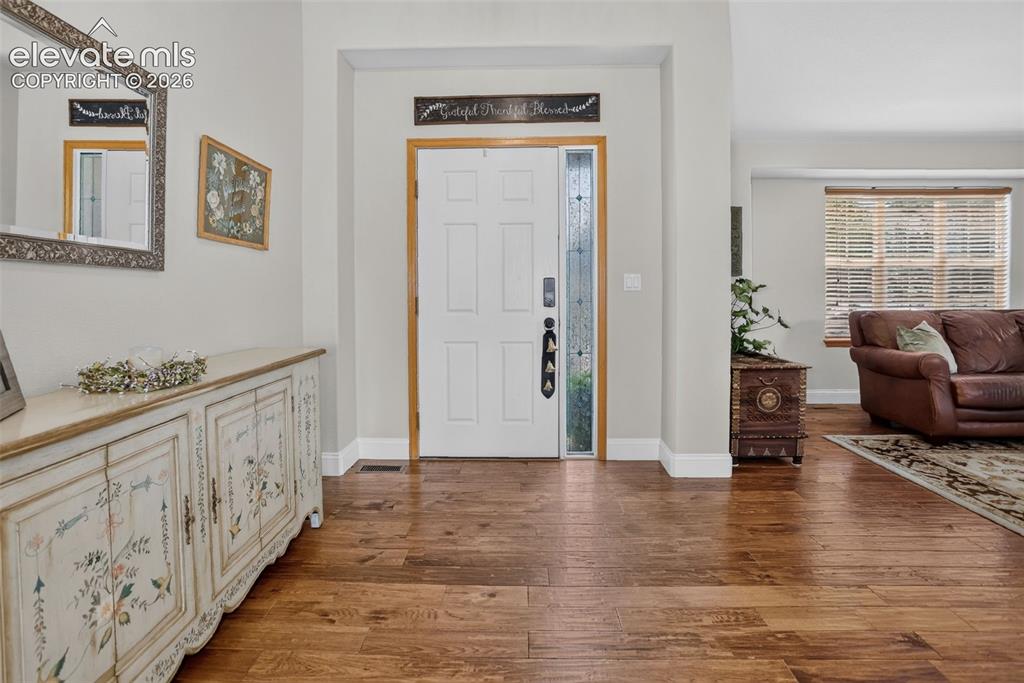 Image 11 of 49: Entryway with wood-finish flooring, a white paneled entry door, and a sidel