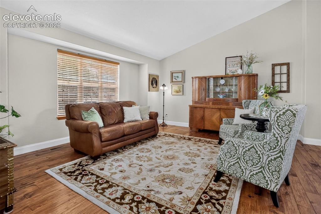 Image 12 of 49: Spacious room featuring vaulted ceilings, wood-finish flooring, and light-t