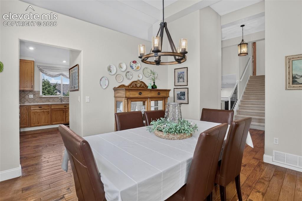 Image 14 of 49: Dining area featuring wood-finish flooring, a contemporary chandelier, and 