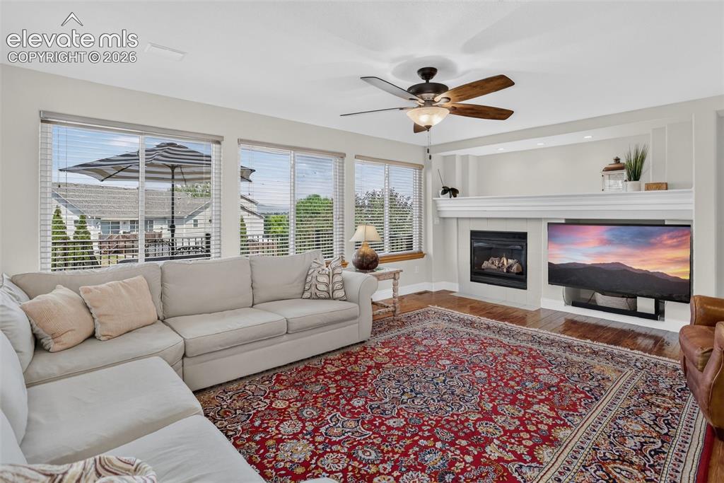 Image 20 of 49: Living room featuring hardwood-finish flooring and a ceiling fan with integ