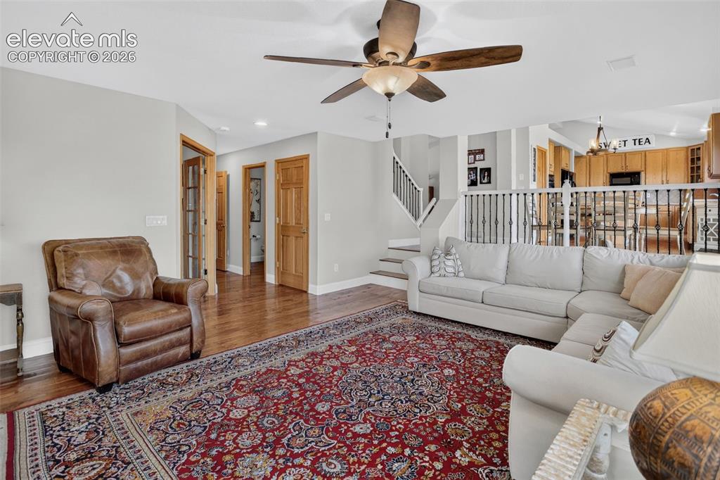 Image 22 of 49: Open living area with wood-finish flooring and a ceiling fan