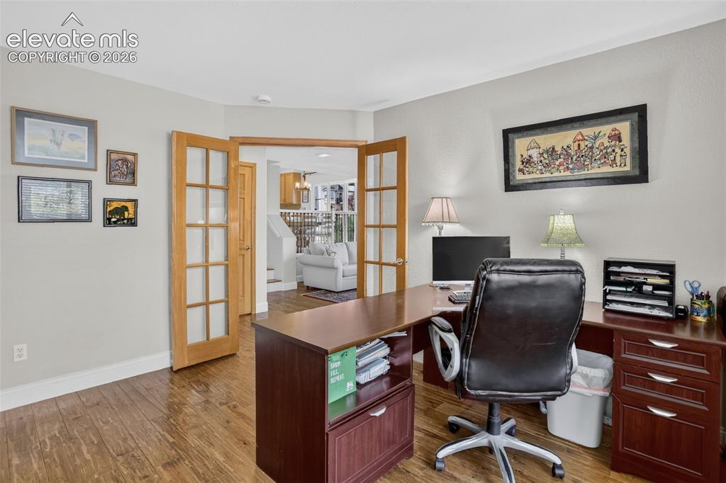 Image 23 of 49: Office space featuring wood-finish flooring, light gray walls, and French d