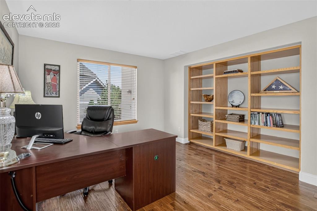 Image 24 of 49: Hardwood-finish flooring complementing built-in shelving, a large window wi