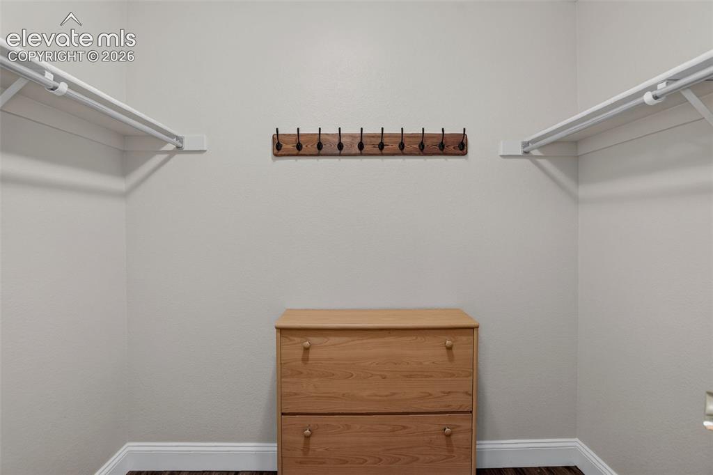 Image 25 of 49: Walk-in closet with white walls, wood-finish flooring, white shelving and h