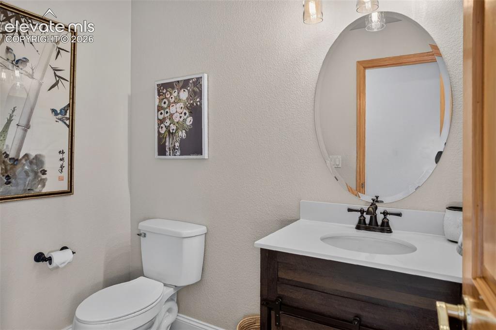 Image 26 of 49: Compact powder room featuring a single-sink vanity with dark wood-finish ca