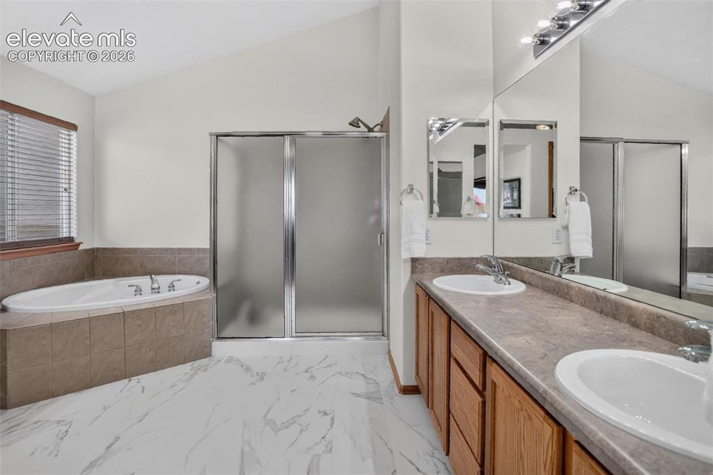 Image 31 of 49: Bathroom featuring a vaulted ceiling, dual vanity with undermount sinks, a