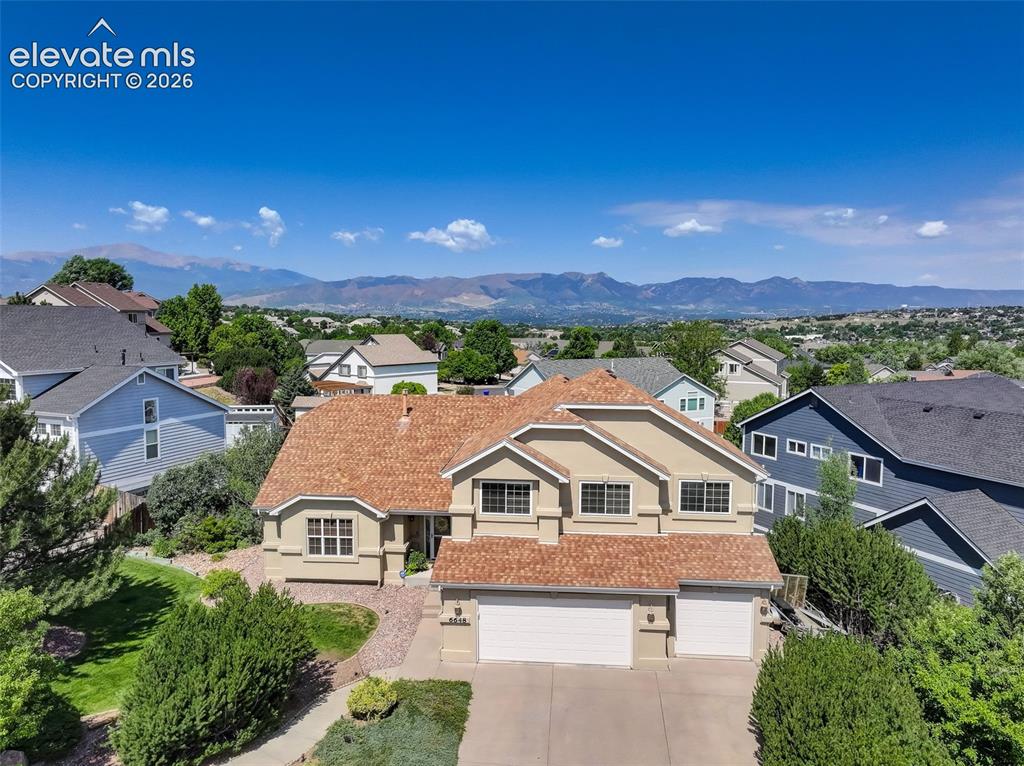Image 5 of 49: Stucco exterior residence with a multi-gabled, terracotta-toned roof, an at
