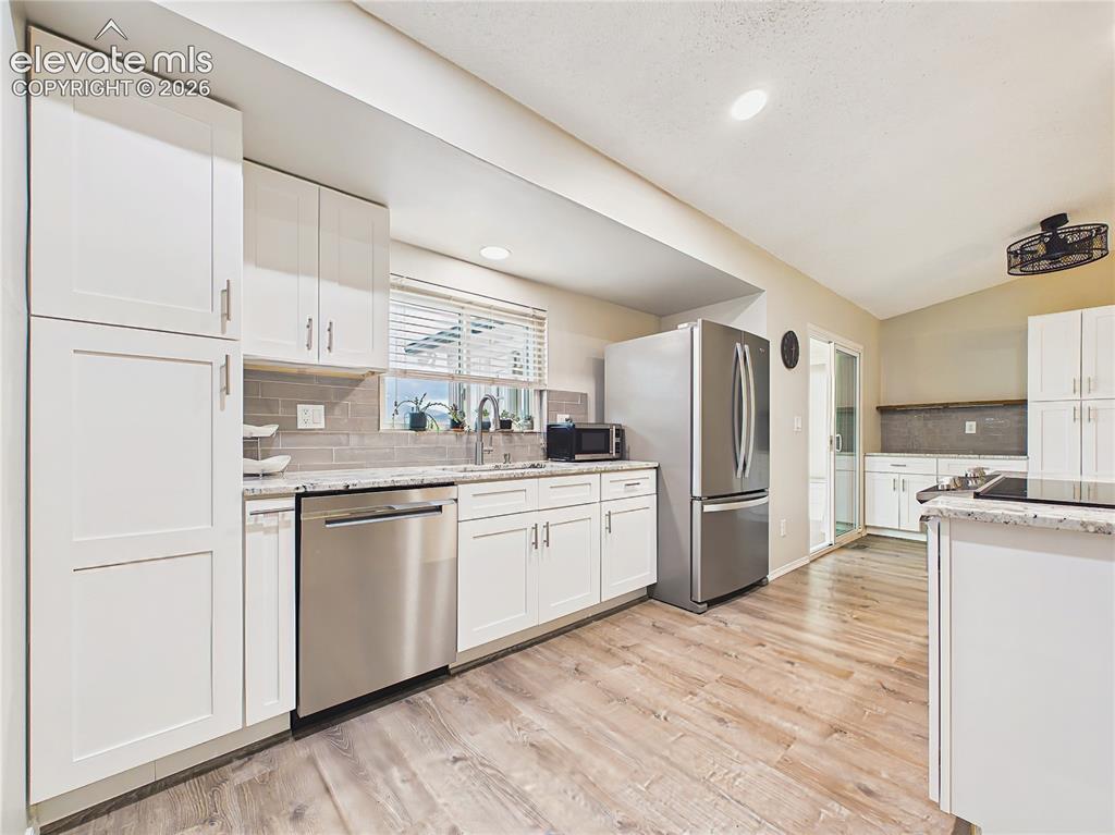 Image 10 of 50: Beautifully updated kitchen featuring white shaker cabinetry, granite count