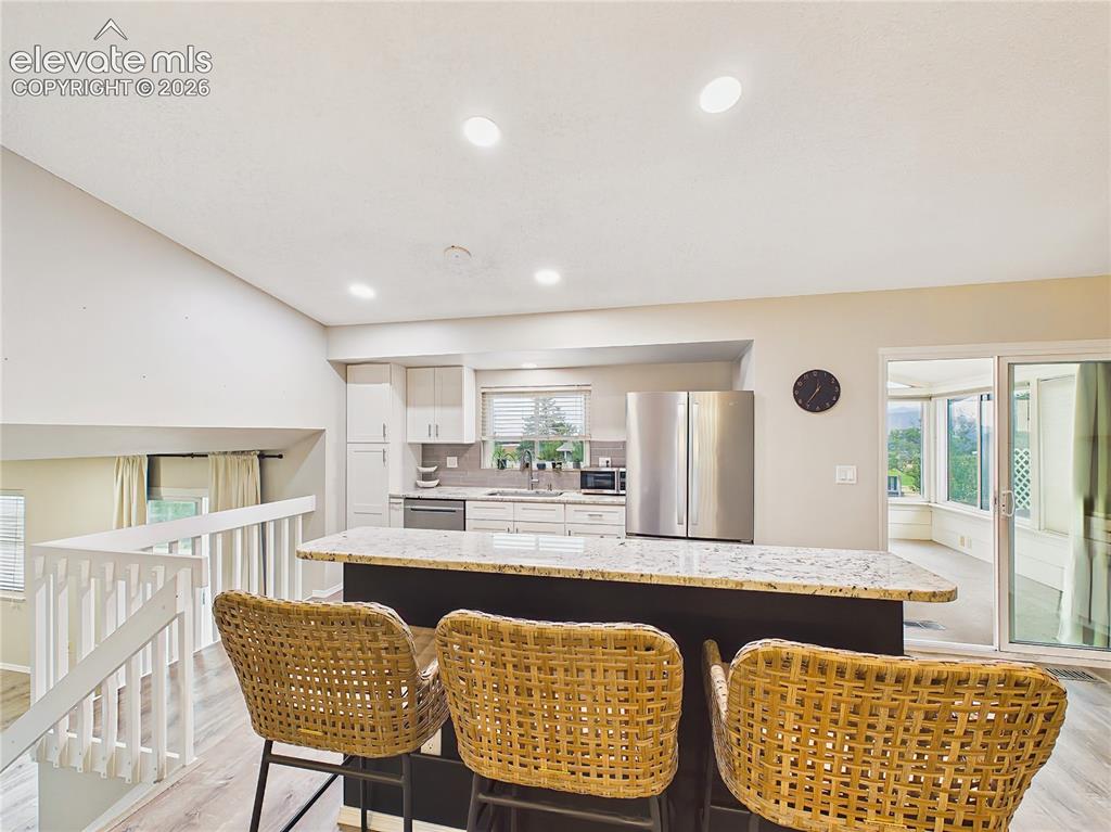Image 18 of 50: Large granite-topped breakfast bar offers comfortable seating, generous wor