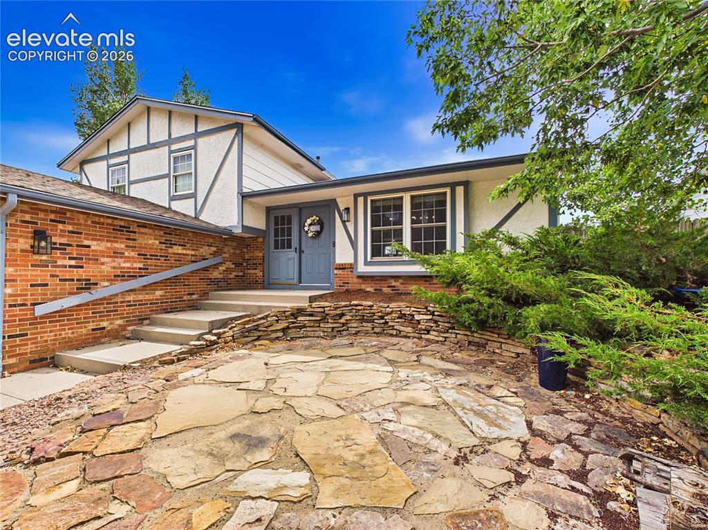 Image 3 of 50: Welcoming front entrance highlighted by a flagstone patio, attractive lands
