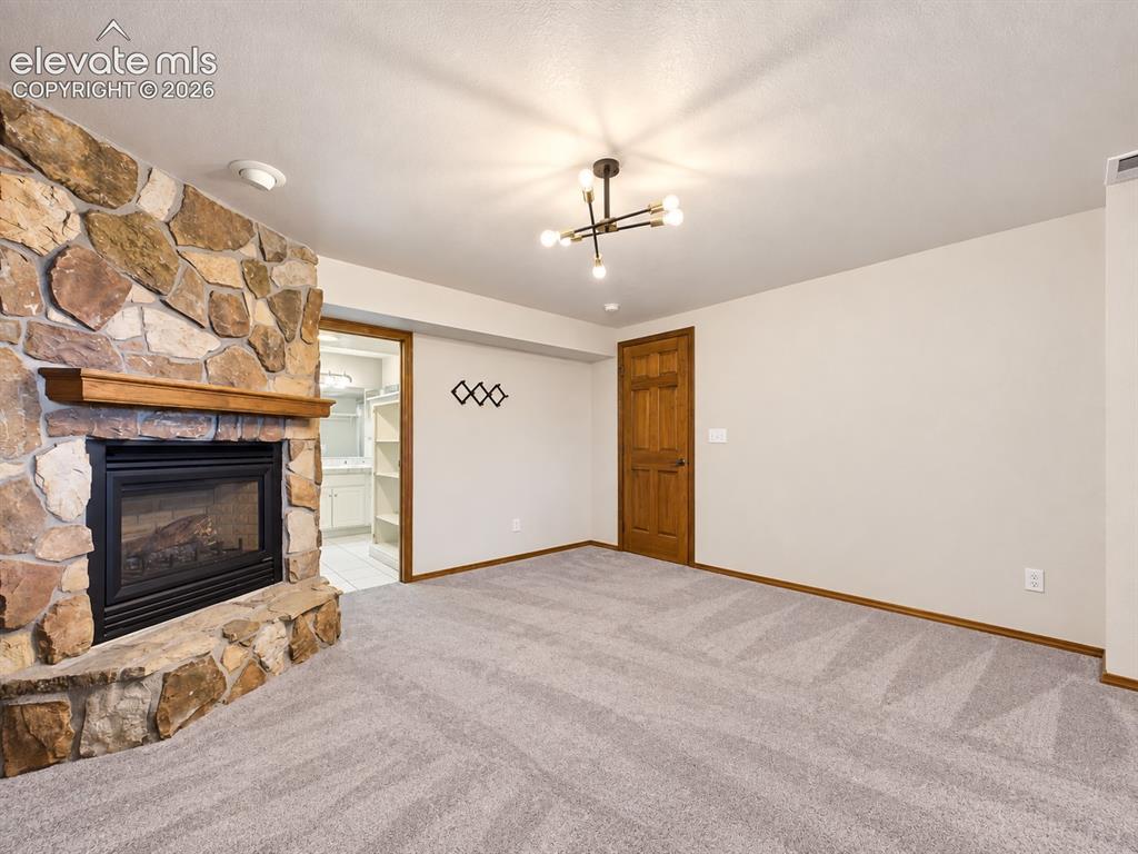 Image 30 of 50: Expansive primary bedroom with a cozy stone fireplace, generous floor space