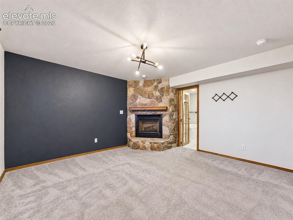 Image 31 of 50: Spacious primary suite highlighted by a beautiful stone fireplace, creating