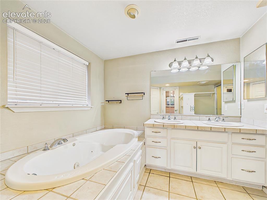 Image 33 of 50: Spacious primary bath with dual vanities, a soaking tub, and ample counter 