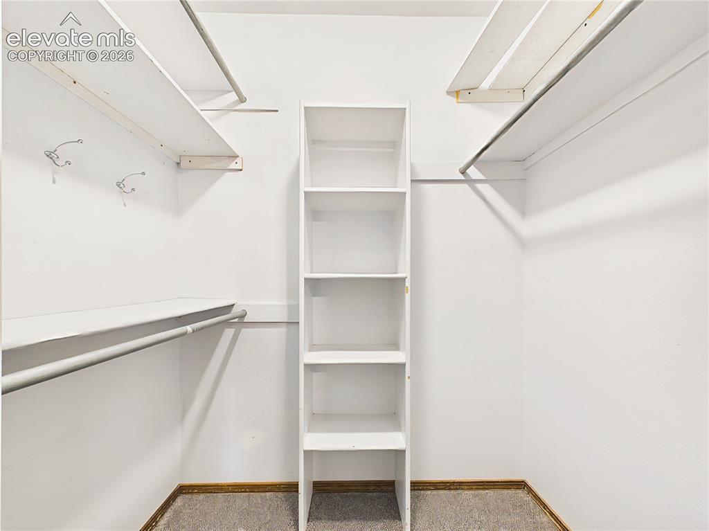 Image 38 of 50: Spacious walk-in closet with built-in shelving and multiple hanging areas t