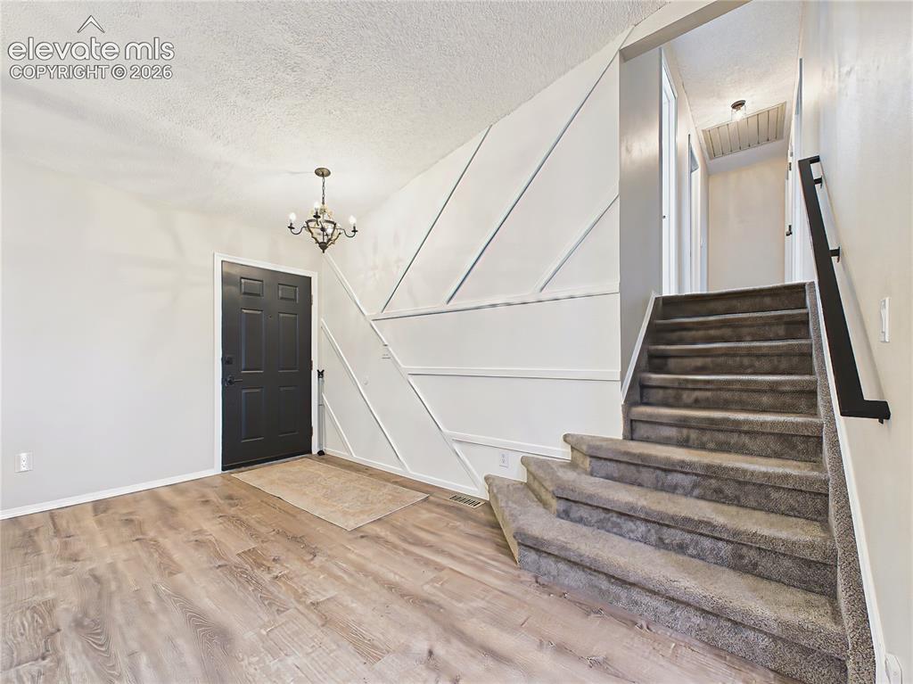 Image 4 of 50: Welcoming entry with updated luxury vinyl plank flooring, modern black fron