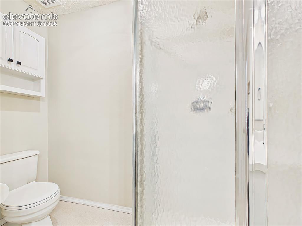 Image 40 of 50: Full bathroom featuring a walk-in shower, convenient storage cabinetry, and