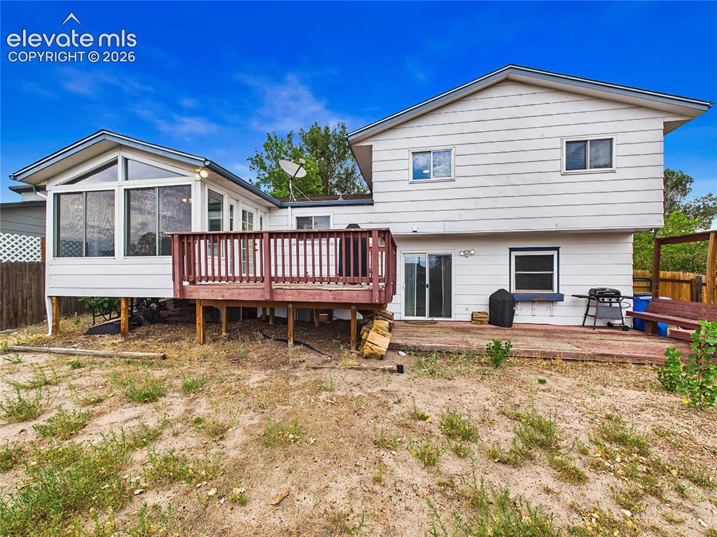 Image 49 of 50: Backyard featuring a spacious deck, enclosed sunroom, and plenty of outdoor