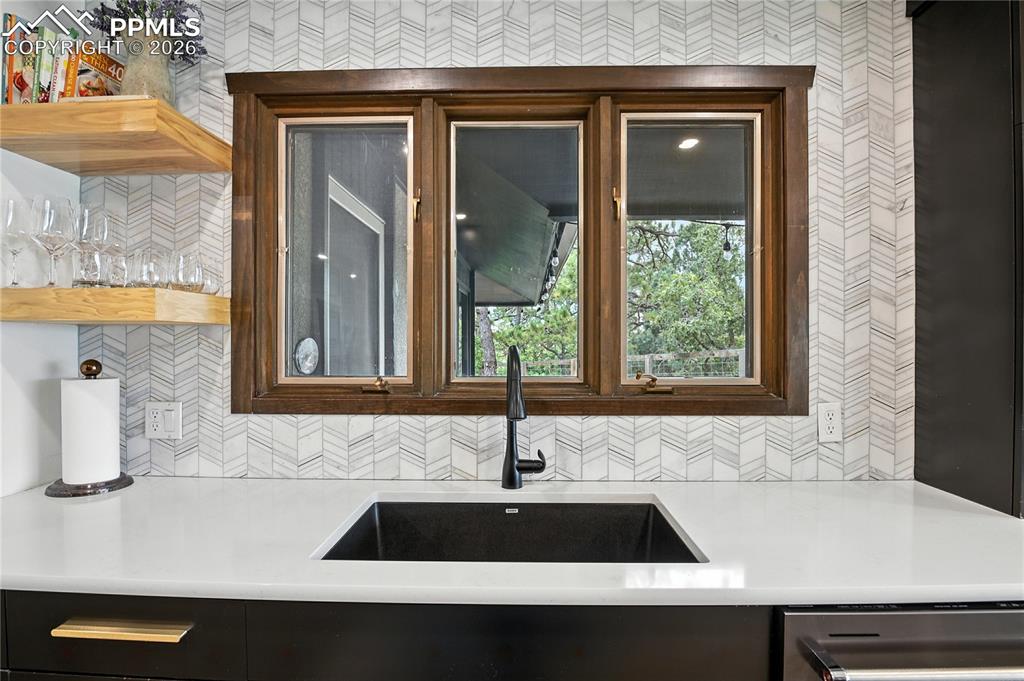 Image 13 of 50: Kitchen featuring tasteful backsplash, light stone counters, and open shelv