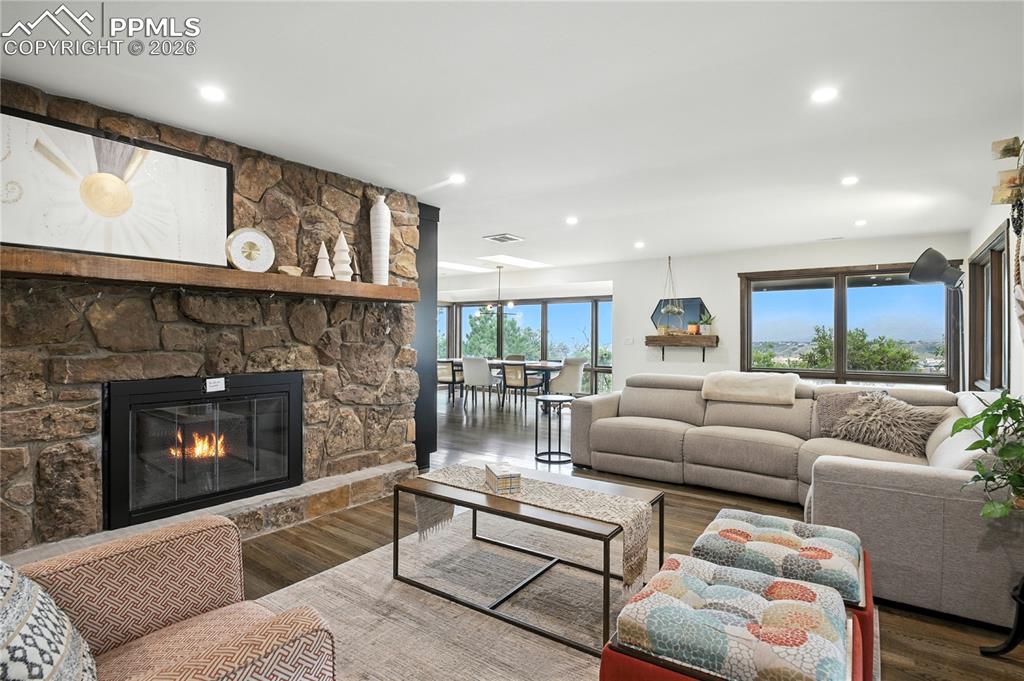 Image 22 of 50: Living area with a fireplace, wood finished floors, and recessed lighting