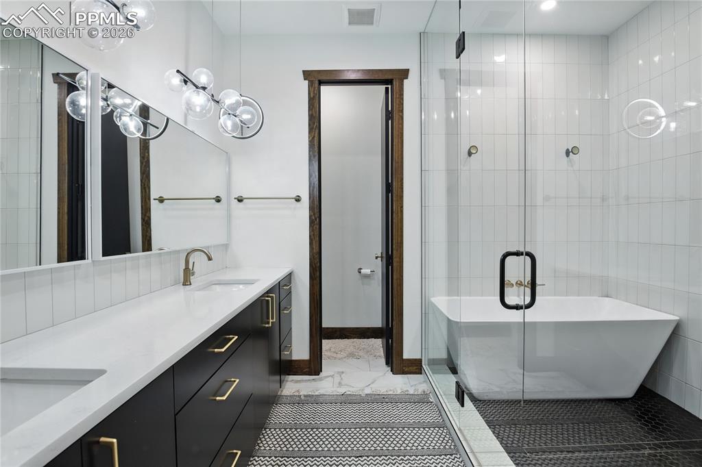 Image 30 of 50: Full bathroom featuring a shower stall, double vanity, and a freestanding b