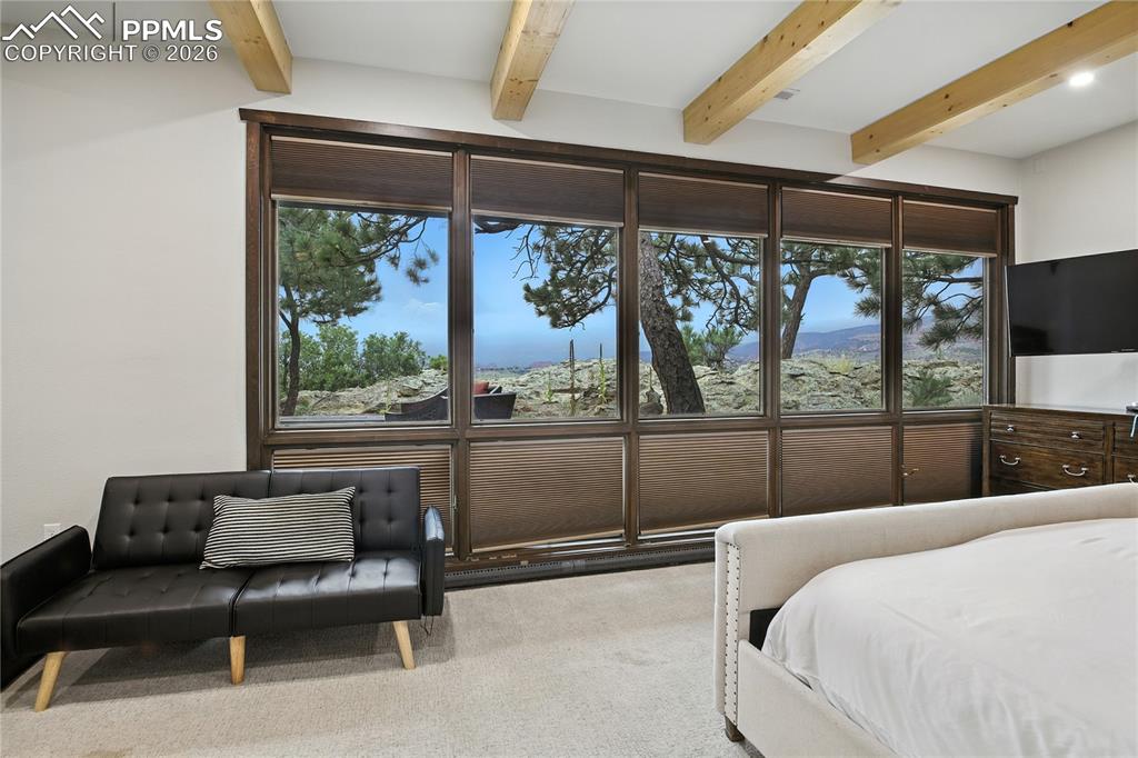 Image 32 of 50: Bedroom with beamed ceiling and carpet floors