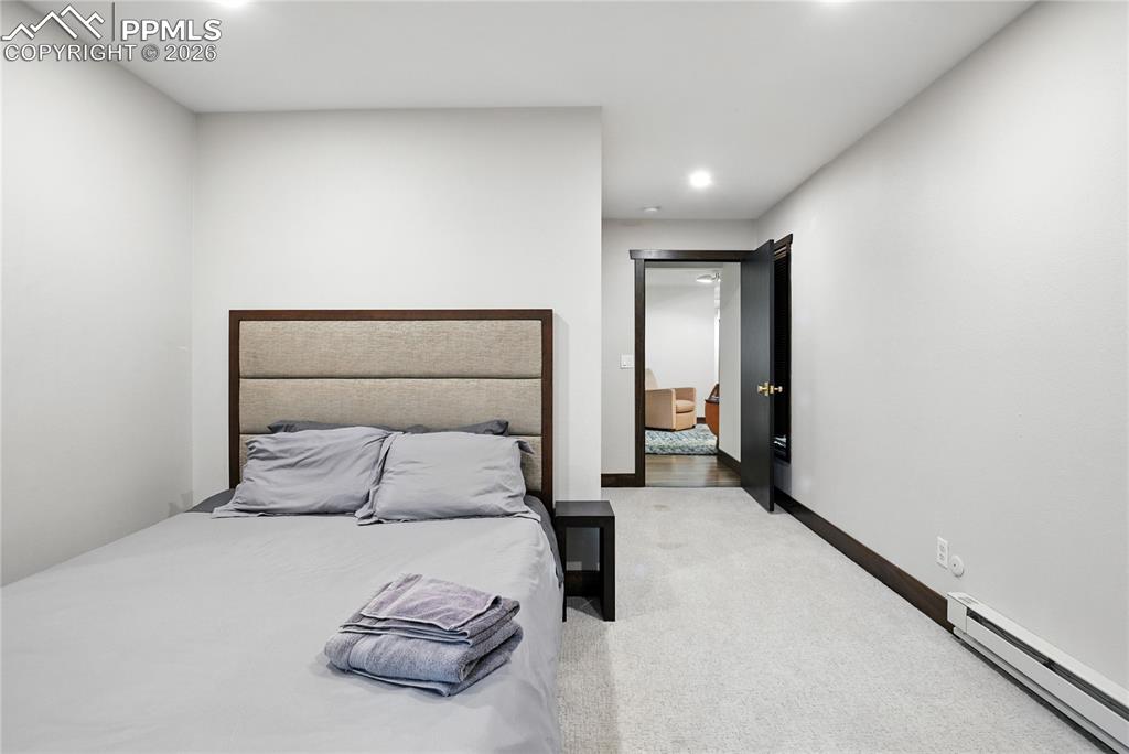Image 44 of 50: Bedroom with baseboard heating, light colored carpet, and recessed lighting