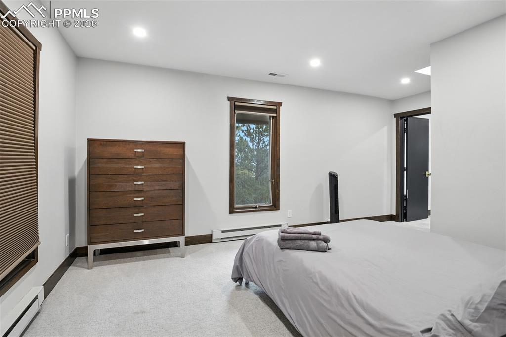 Image 45 of 50: Bedroom with recessed lighting, light colored carpet, and a baseboard heati