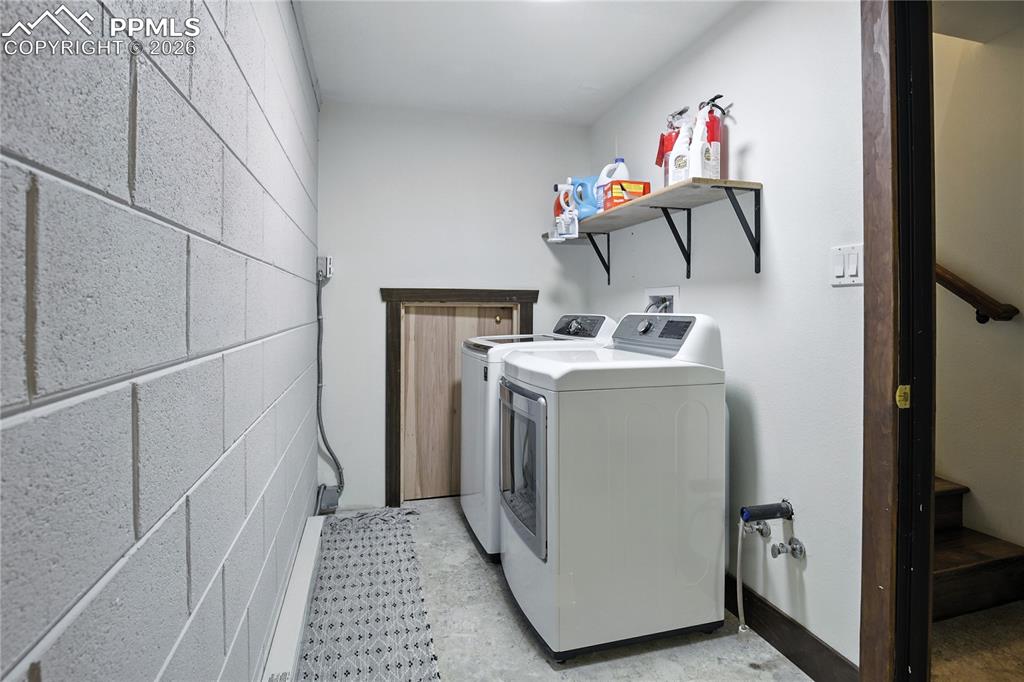 Image 48 of 50: Laundry area featuring separate washer and dryer and concrete block wall